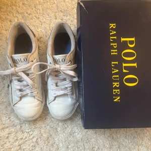 Polo Ralph Lauren skor - Säljer mina snygga vita sneakers från Polo Ralph lauren med mörkblå detaljer, använda fler tal gånger men har tvättat dom är de är i rätt bra skick, små hål i innertyget (bild 4), samt en minemal gul fläck på sulan (bild 5)💕 Skriv vid frågor eller för fler bilder💕 Priset är diskuterbart!