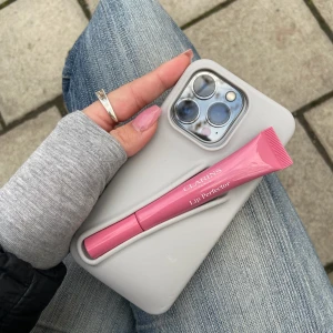 Mobilskal med läppglanshållare från Amore UF - Mobilskal med en inbyggd hållare för olika läppglans i färgen grå för IPhone 13/14/15 PLUS. Den rymmer flera olika läpprodukter och ger bra skydd för mobilen🥰🥰perfekt för tillfällen där du inte vill ha en väska med dig!