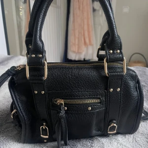 Svart handväska med dragkedja - Snygg svart handväska med gulddetaljer. Knappt använd så den är som ny.