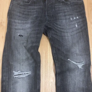 Svarta/grå jeans från Jack & Jones - Feta jeans med slitningar. Skick:10/10 använd bara vid test o dom passade inte mig.