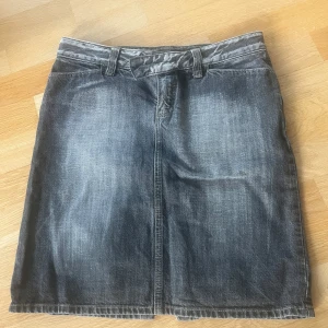 Jeanskjol med slits - Snygg jeanskjol från Massimo Dutti i en klassisk grå tvätt. Kjolen har en stilren design med slits baktill och bälteshällor i midjan. Perfekt för en avslappnad look.    Kvalitet 100% bomull. Storlek 40 närmare 38. 