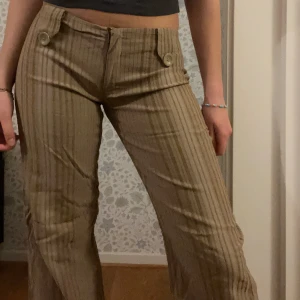Beige randiga byxor med knappar - Snygga beige byxor med randigt mönster 
