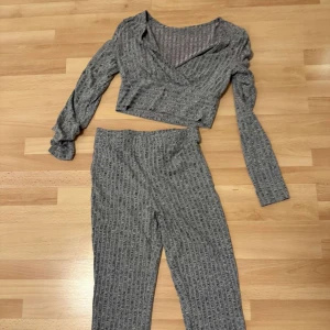 Grå ribbad croppad tröja - Säljer en grå ribbad croppad tröja med omlott-design. Tröjan har långa ärmar och en stilren look som passar perfekt för en avslappnad stil. Perfekt för dig som gillar en modern och bekväm outfit.