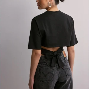 Svart nelly topp med knyt - Snygg svart kortärmad topp med knyt i ryggen från Nelly. Perfekt för en stilren look med en twist. Passar bra till jeans eller kjol. Skriv för fler bilder💞skriv så sätter jag på köp nu