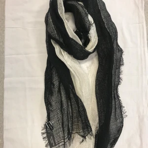 Svart och vit halsduk  - Snygg och luftig halsduk i svart och vitt från No Name. Den har en nätliknande struktur som ger en cool och avslappnad look. Perfekt för att lägga till en touch av stil till din outfit.  Mått 188.00*66.00 cm . 50% bomull, 50% linne , 
