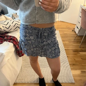 Mönstrad byxkjol i blått och vitt - Snygg mönstrad kjol med inbyggda shorts 💕 den är i blått och vitt med volangdetaljer. Perfekt för en somrig look. Kjolen har en bekväm passform och är lätt att matcha med olika toppar. 
