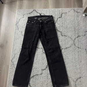 Svarta jeans från Weekday - Snygga svarta jeans från Weekday med en klassisk design. De har en rak passform och är tillverkade i ett slitstarkt denimtyg. Perfekta för en stilren look.