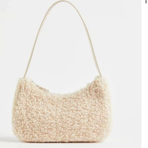 Beige axelväska i teddy-material - Säljer denna beige färgade  söta väska från H&M. Aldrig använd. Skirv för fler bilder💕 Pris kan diskuteras!