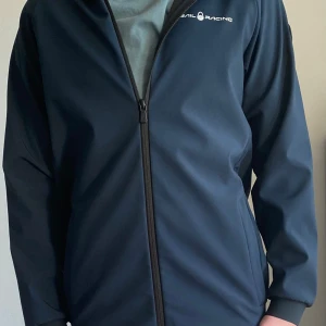 Marinblå jacka från Sail Racing - Säljer en stilren marinblå jacka från Sail Racing. Luvan ligger lite konstigt men den är helt normal jag lovar! Ställ gärna frågor och du kan lägga bud! Märket är lite skrapigt. Retail på cirka 1200kr 