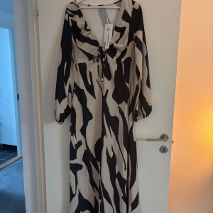 Zebramönstrad klänning med ballongärmar - Snygg zebramönstrad klänning med ballongärmar och v-ringning från NAKD. Aldrig använd med lapp kvar. Säljer då jag inte hann returnera. Nypris 549kr
