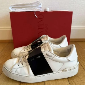 Valentino Garavani sneakers i vitt och svart  - Säljer nu dessa extremt snygga valentino open i strl 38,5. De är i otroligt fint skick och box+dustbag+kvitto och extra snören medföljer. Skriv för frågor eller funderingar! 