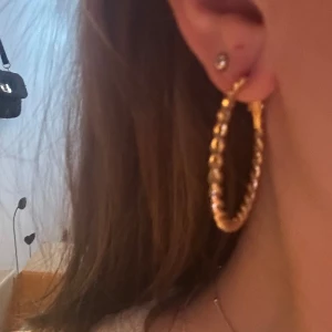 Guldiga vridna örhängen - Snygga guldiga örhängen med en vriden design. Perfekta för att ge en elegant touch till din stil. De är runda och har en enkel låsmekanism för säker användning.