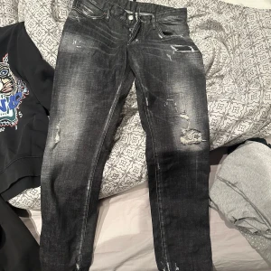 Svarta jeans från Dsquared2 - Snygga svarta jeans från Dsquared2 med slitna detaljer och en cool, tvättad look. De har en klassisk femficksdesign och knappar i gylfen. Perfekta för en trendig stil. Använda vid ett tillfälle, köpta ifrån farfetch för 3100.