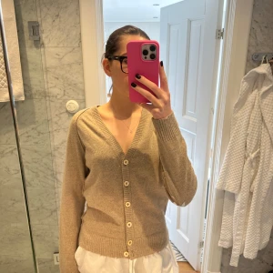 Beige kofta från Zadig & Voltaire -  snygg beige kofta från Zadig & Voltaire med silverstjärnor på ärmarna. Koftan har en v-ringad design och knappar framtill. 