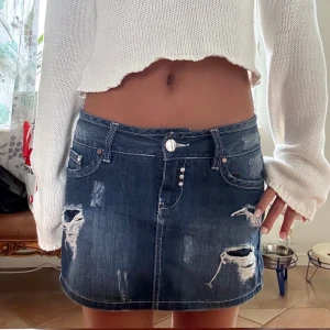 Jeanskjol med slitningar - Säljer en blå jeanskjol med jätte coola slitningar och nitar. Midjemåttet på kjolen är 39 cm💗