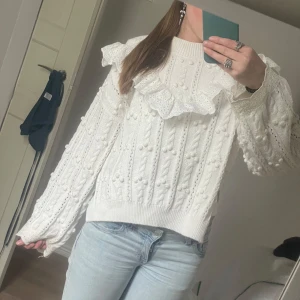 Vit stickad tröja med volang - Superfin vit stickad tröja med dekorativa volanger och strukturstickat mönster. Tröjan har lång ärm, ribbade muddar. Har endast använts ett fåtal gånger, storlek XS men passar även S🩷💗