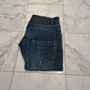 Mörkblå jeans från dondup - Snygga mörkblå jeans från dondup med klassisk femficksdesign och kontrastsömmar. De har en straight passform och är perfekta för en avslappnad stil. Jeansen har en knappgylf och är tillverkade i slitstarkt denim. Vid frågor eller funderingar är de bara att höra av sig💯