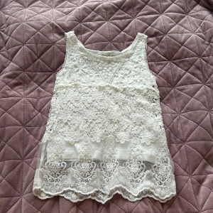 Vit spetslinne från L.O.G.G. - Säljer ett superfint vitt linne från L.O.G.G. i storlek 134/140. Linnet har vacker spets med blommönster och broderade detaljer samt en lätt transparent nederdel. Perfekt för sommardagar eller speciella tillfällen! Den har ett vitt linne på insidan🤍