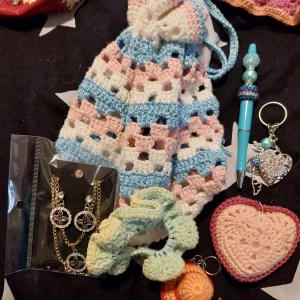 Grön och vit virkad axelväska - Säljer en handgjord virkad axelväska i grönt och vitt med ränder och botten i rött konstläder. Väskan har ett retroinspirerat mönster och axelrem. Perfekt för dig som gillar unika accessoarer. Finns 5 pkt av dessa säljes styck vis för 300 kr per paket 