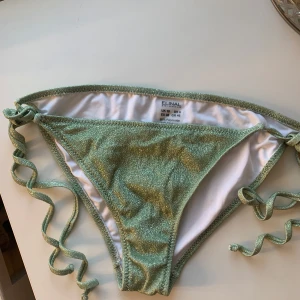 Nytt glittriga gröna bikinitrosor - Helt nytt men klistermärket inuti har lossnat.Snygga gröna bikinitrosor med glittrigt från putik i Greece (Elinal Swimwear). Storlek 38