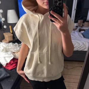 Beige ärmlös hoodie - Säljer en beige hoodie utan ärmar med luva