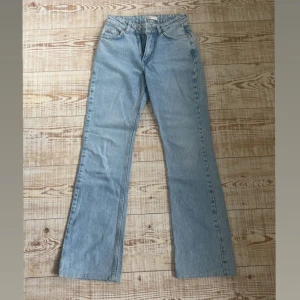 Bootcut jeans - Säljer ett par ljusblå mid waist jeans från gina tricot då dom har blivit för små, de är uppsydda så innerbenslängden är 77cm och midjemåttet tvärs över är 33cm💕 hör av er vid frågor. 