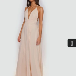 Ljusbeige långklänning med djup v-ringning - Supersnygg ljus rosa långklänning i storlek xs från ivory field med djup v-ringning och tunna axelband. Klänningen har öppen rygg och ett flowy fall, perfekt för bal eller fest. Materialet känns lätt och elegant. Aldrig använt och har inte tagits upp ur förpackningen den kom i. Har även en likadan som inte packats upp i storlek s. 