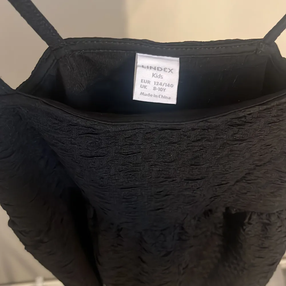 Säljer ett svart gulligt linne från Lindex med smala axelband och strukturerat tyg. Perfekt för dig som vill ha en enkel men snygg look. Linnet har en lätt utställd passform och är superenkel att styla. . Puserot.