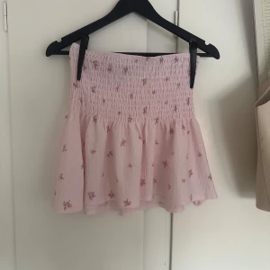 Ljusrosa blommig kjol från Gina Tricot - Supersöt ljusrosa kortkjol från Gina Tricot med små blommor och smock i midjan. Köpt i slutet på förra sommar 2024 så max använd 4 gånger! Skriv vid intresse eller fundering!❤️