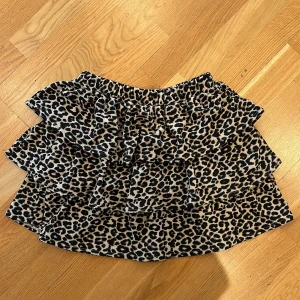 Leopardmönstrad volangkjol från Kappahl - Säljer en superfin kort volangkjol från Kappahl med leopardmönster. Kjolen har flera lager volanger och resår i midjan för en bekväm passform. 