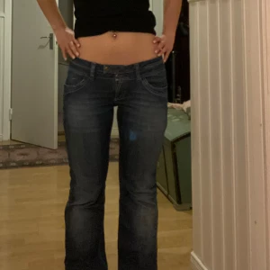 Blå jeans från VILA - Snygga lågmidjade bootcut jeans från VILA med klassisk femficksdesign och knappgylf. Perfekta för en avslappnad stil. Passar mig som är 170 och brukar ha S/M