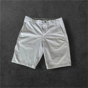 Vita golf shorts från Puma - Snygga vita shorts från Puma med klassisk design och raka ben. Shortsen har fickor fram och bak samt bälteshällor i midjan. Perfekta för sommardagar eller sportiga aktiviteter.