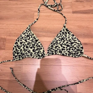 Leopardmönstrad trekantsbikini - Säljer en trekantsbikini med leopardmönster i svart och neon grön. Bikinin har knytband i nacken och ryggen. Perfekt för sommaren och strandhäng!