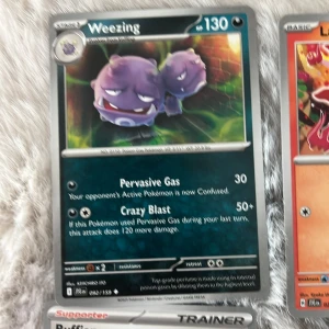 Pokémonkort - Weezing, Larvesta, Cubone, N's Zorua, Wailmer - Säljer fem Pokémonkort: Weezing (mörkgrå/lila), Larvesta (vit/röd), Cubone (brun/blå), N's Zorua (svart/grön), och Wailmer (blå/vit). Alla kort har färgstarka illustrationer och tydliga Pokémonmotiv. Perfekt för samlare eller Pokémonfans!