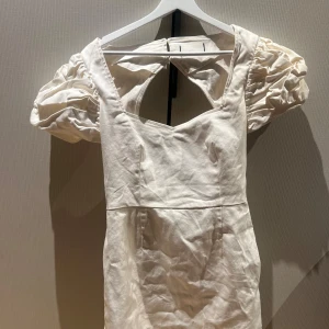 Vit kort puffärmad klänning med öppen rygg - Säljer en söt vit kortklänning med puffiga kortärmar och öppen rygg. Klänningen är i vitt jeans tyg.