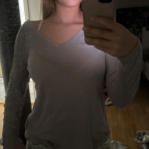 Ljusgrå långärmad tröja från Kappahl - Säljer en enkel och stilren ljusgrå långärmad tröja från Kappahl. Tröjan har v-ringning och har ett tunt material. Perfekt basplagg att ha i garderoben!