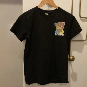 Svart t-shirt med nalle från Barrow - Svart t-shirt från Barrow med färgglad nalle-tryck på bröstet och större nalle-tryck på ryggen. Texten 'I just want to feel good' finns under nallen på baksidan. Klassisk passform och rund hals.