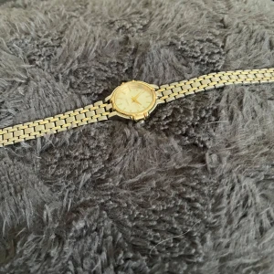Guldfärgad damklocka med länkarmband - Stilren guldfärgad damklocka med klassiskt länkarmband och rund urtavla. Urtavlan är enkel med guldiga markeringar och visare. Perfekt accessoar för dig som gillar en elegant look.