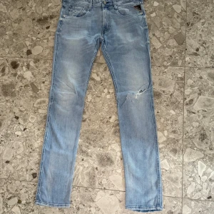 Ljusblå Replay Anbass jeans - Säljer ett par snygga ljusblå Replay Anbass jeans till ett väldigt bra pris. Storleken är midja 32 och längd 34. De har en liten reva på ena benet. Perfekta för dig som vill ha ett par feta jeans.