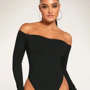 Svart offshoulder bodysuit - Snygg svart bodysuit med offshoulder-design och lång ärm. Perfekt för att skapa en stilren och trendig look. Tight passform som framhäver figuren. Storlek M men passar även S