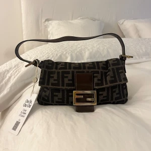 Fendi baguette - Säljer fendi baguette väska som jag aldrig användt(lappen är kvar) jag köpte väskan på Vestiaire collective utan vetskapen att man ej kunde lämna tillbaks😅när jag köpte väskan betalade jag extra för att de skulle göra äkthetsbevis så man är säker på att den var äkta. Och det var den, väskan är jättefin och i bra tillstånd☺️