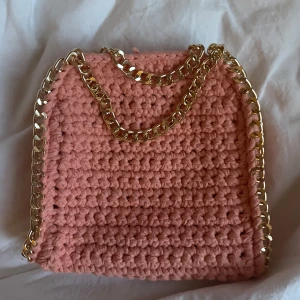 Stella McCartney liknande väska  - Egengjord ljus orange/rosa väska som är perfekt till vår/sommar! 🧡🩷Har guld kedja runt och även en vid axeln så den går att hänga runt (se bild). Vill ni ha tydligare bild på den kolla våra videos på TikTok, där heter vi också crochetsellout!! Skriv vid eventuella frågor!! 