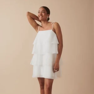 Vit volangklänning  - Säljer en söt vit kortklänning med volanger. Köpt till studenten men valde en annan klänning så därav är den helt oanvänd! Orginalpriset är 700kr