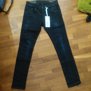 Svarta slim jeansbyxor från Dondup. Helt nya, med tags(utan kvitt). - Säljer ett par svarta jeansbyxor från Dondup med fem fickor och smal passform. Byxorna har klassisk design med knapp och dragkedja framtill samt bälteshällor. Perfekta för dig som gillar en stilren look.