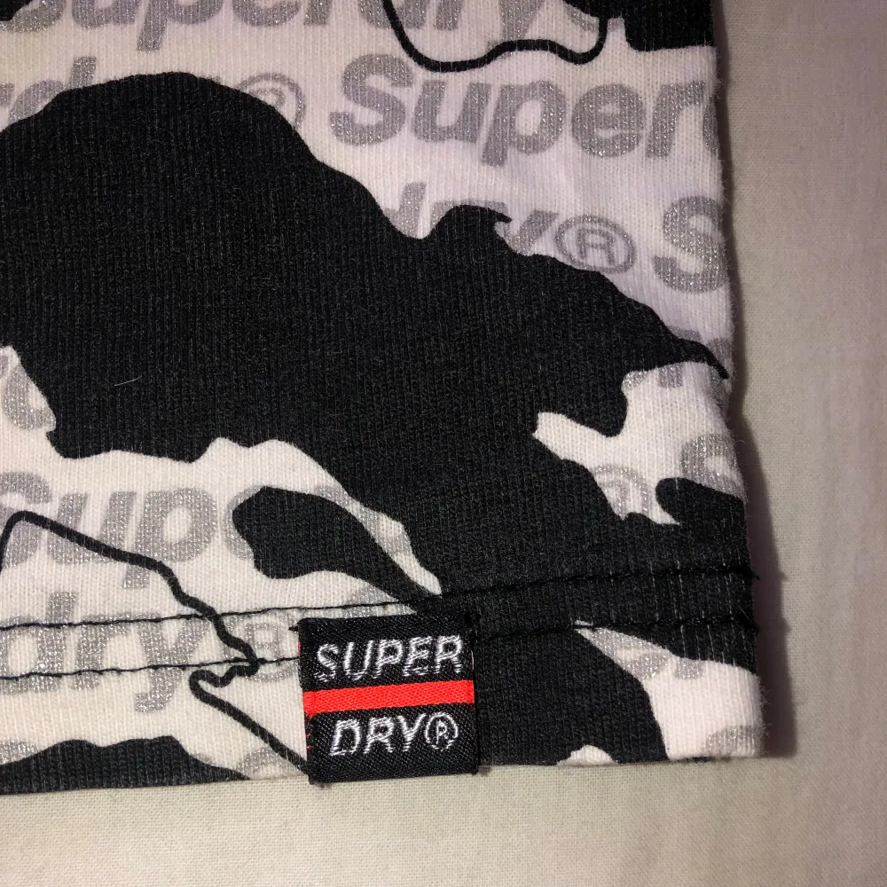 Säljer en svartvit t-shirt från Superdry med camouflagemönster och tydlig logga på bröstet. (“T” lifter lite som man ser i bild 2, säkert går att limma). T-paidat.