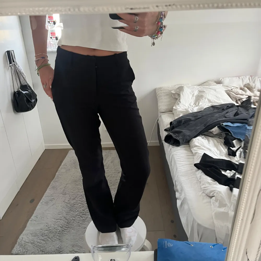 Säljer ett par klassiska svarta kostymbyxor med rak passform och hög midja. Byxorna har diskret dragkedja framtill och är tillverkade i ett mjukt material som ger en dressad look. Perfekta för en stilren outfit. Litet igensytt hål i knät men inget som syns. Farkut & Housut.