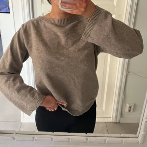 Beige stickad tröja med rund hals - Säljer en enkel och stilren beige stickad tröja med rund halsringning och breda muddar vid ärmslut och nederkant. Har ett litet litet hål, inget man ser
