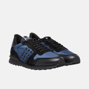 Valentino Garavani Rockrunner i blått och svart - Säljer ett par snygga Valentino Garavani Rockrunner sneakers i en cool kombination av blått och svart. Skorna har en unik design med de ikoniska nitarna på sidorna och en bekväm snörning. Perfekta för både vardag och fest!