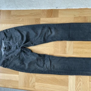 Grå jeans från Nudie Jeans Co - Säljer ett par grå jeans från Nudie Jeans i storlek 34. De har en klassisk femficksdesign och är i bra skick. Perfekta för både vardag och fest!