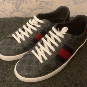 Gucci ace skor - Säljer ett par Gucci Ace sneakers i storlek 43, nästan oanvända och i nyskick. Klassisk vit design med de ikoniska marinblå och röda ränderna. Perfekt för dig som vill ha lyxiga och tidlösa sneakers! Obs inget og